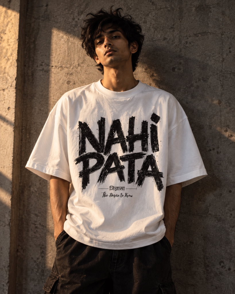 Man in a white Nahi Pata oversized tee with large custom lettering against a raw concrete wall